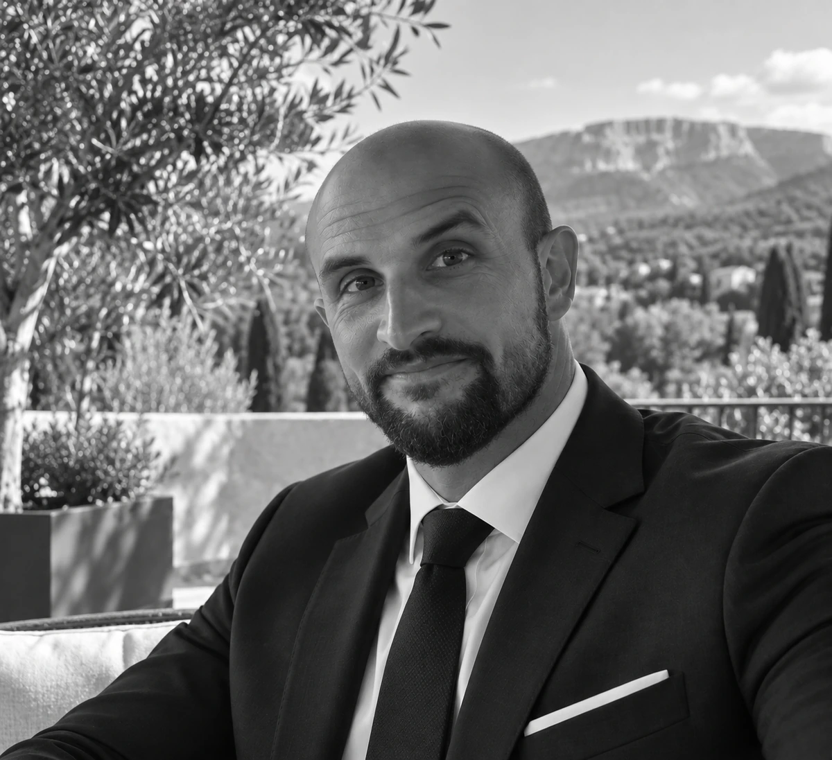 Portrait en noir et blanc d’un homme en costume dans un décor provençal