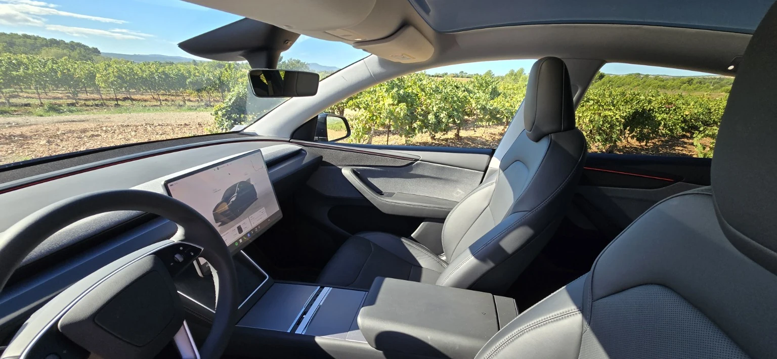 L’habitacle avant de la Tesla Model Y de LAST SMILE, avec ses sièges noirs et les vignes provençales en arrière-plan